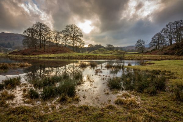 Winter afternoon at Elterwater with the sunlight shining through the clouds, in the Langdale valley, Lake district, England, UK.